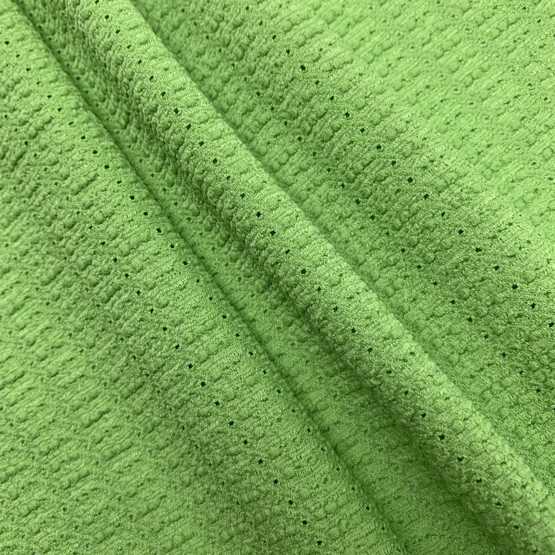 Close up of lace knit fabric showing hollow-out crinkle texture and stretch