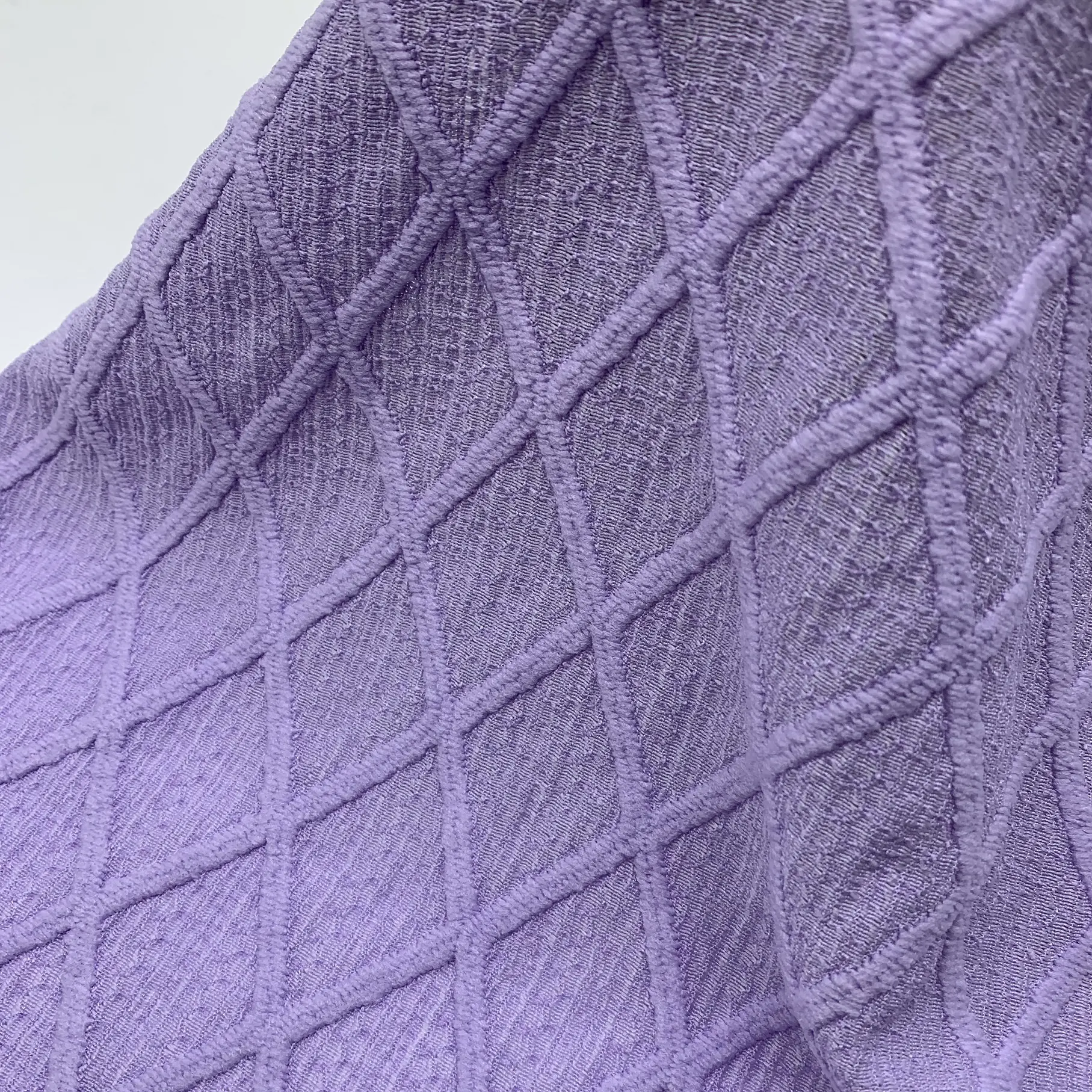 Close up of diamond jacquard crepe fabric showing raised 3D pattern and texture